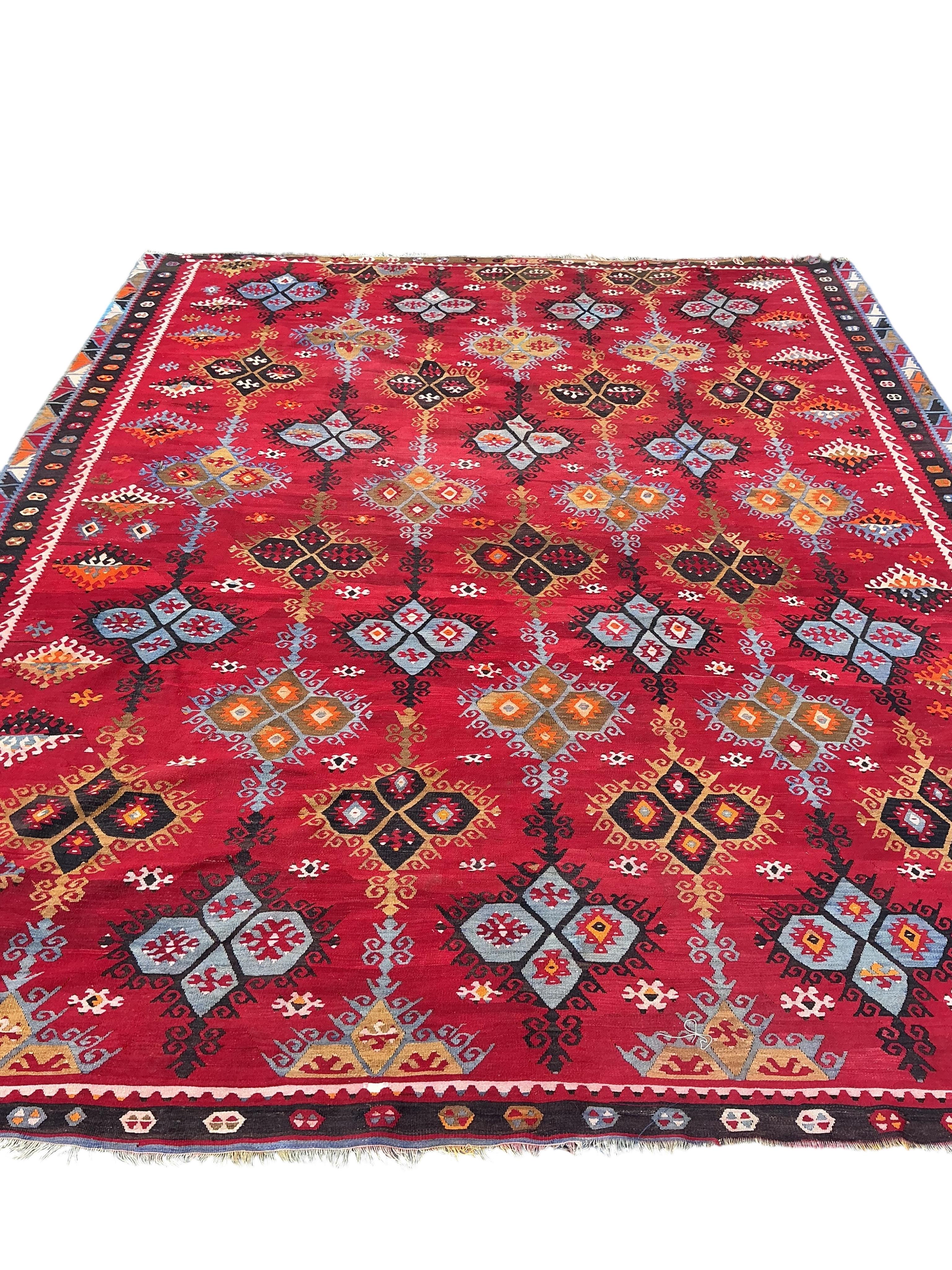 A Turkish Anatolian polychrome flatweave Kilim carpet, woven with geometric lozenges on a red field, 367 x 292cm